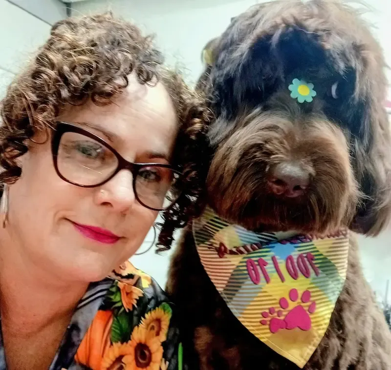 Rose’s Grooming House groomer posing with a freshly groomed chocolate labradoodle